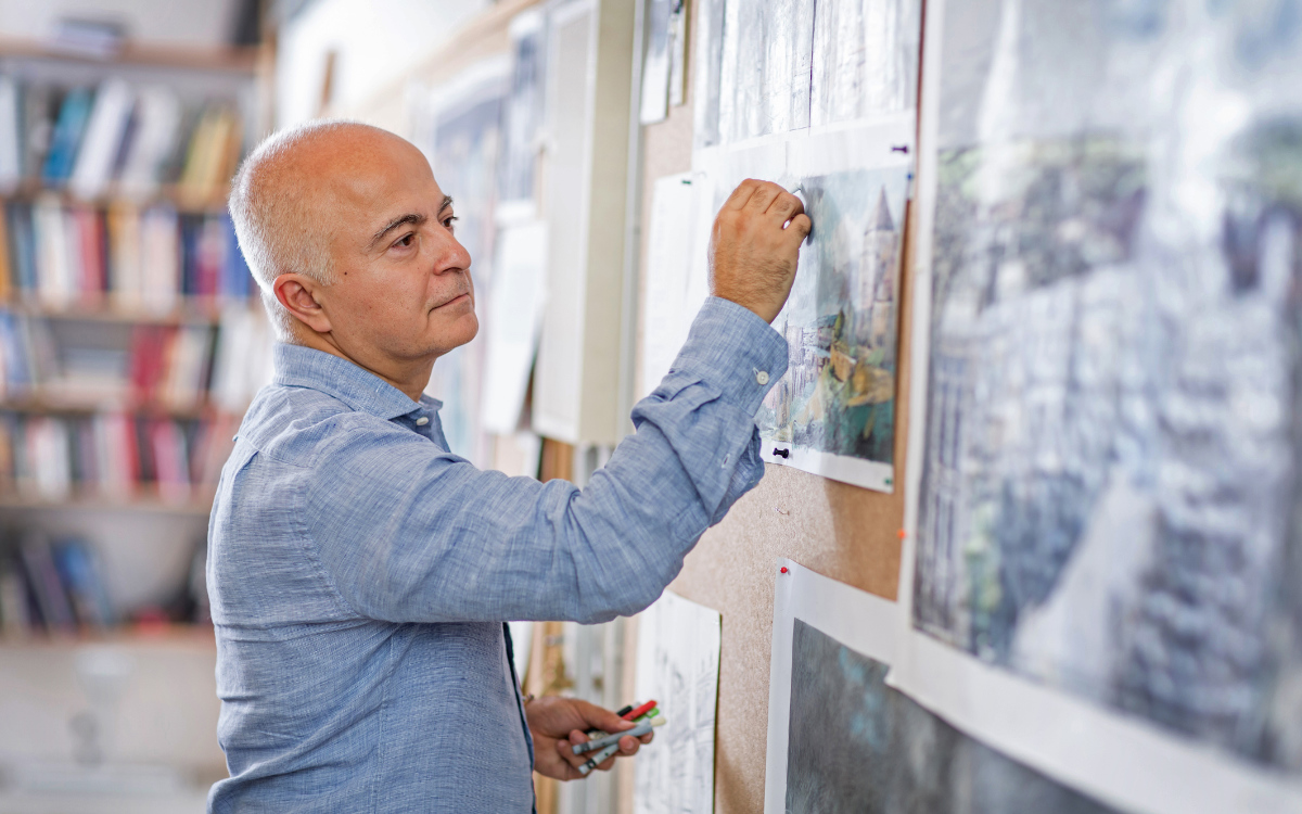 Artist Yadegar Asisi stands inside a panoramic building beneath a wide-span, delicate roof structure.
