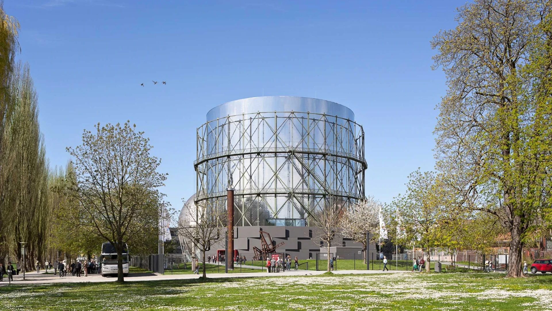 Exterior view of the Gasometer in Pforzheim, set among trees and a meadow under a blue sky